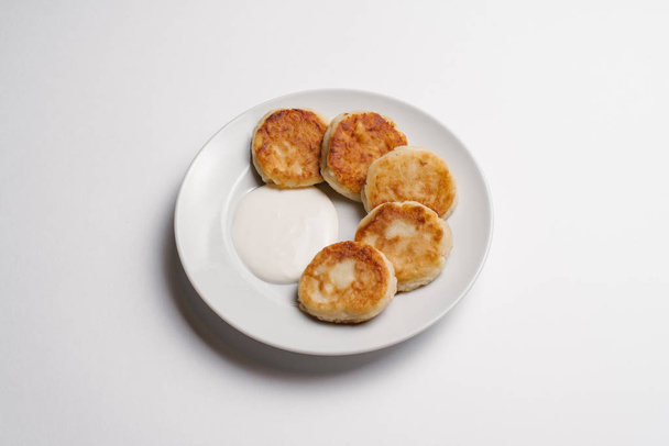Crema di formaggio frittelle con panna acida servita in ciotola bianca isolata su sfondo bianco
 - Foto, immagini