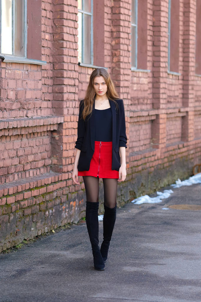 Street fashion, urban style. Girl in jacket, t-shirt, short skirt and high boots - 写真・画像