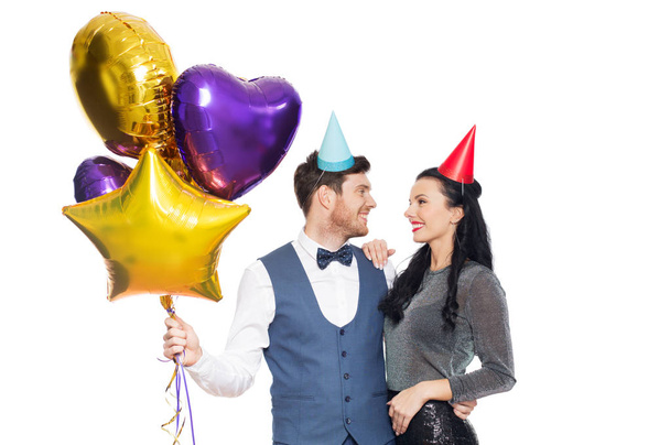 gelukkige paar met partij caps en ballonnen - Foto, afbeelding