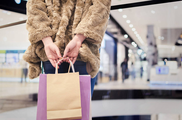 Back view of a fashion shopper woman in coat with shopping bags - Foto, imagen