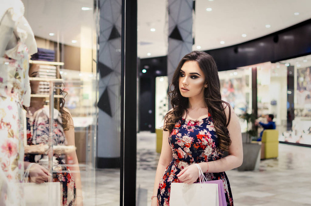 young woman in shopping with bags, walking around boutique and looking clothes - Fotografie, Obrázek