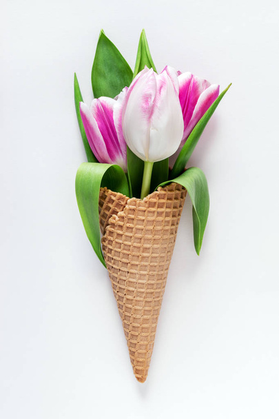 Ice cream cone with tulip flowers on white background.  - Fotó, kép