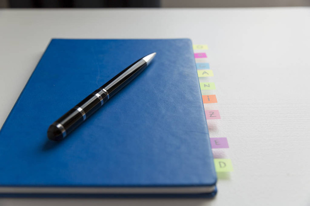 Blue note-boek met pen- en kleurrijk post-it scheidingstekens tussen  - Foto, afbeelding