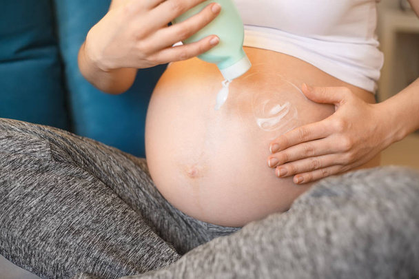 pregnant woman applying cream on her belly - Фото, зображення