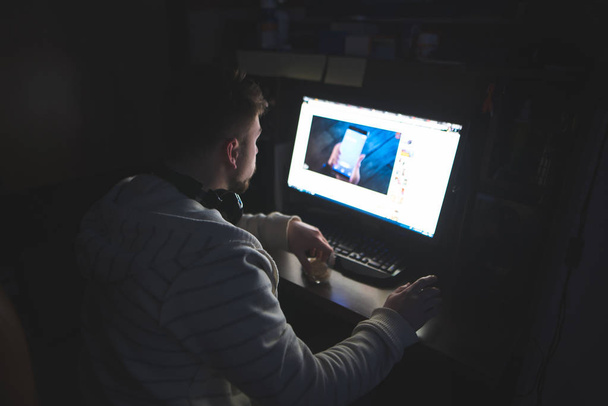 Mój mąż pracuje w domu przy komputerze w nocy. Nocne surfowanie w Internecie. - Zdjęcie, obraz