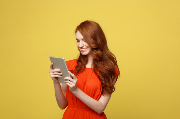 Business Women, Smiling business woman, Business lady, Work concept: Portrait of smiling charming redhead young woman with working on tablet isolated over bright yellow background. - Foto, imagen