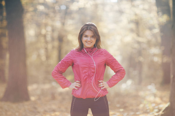 Portrait of a girl who trains and listens to music in the morning autumn park - Foto, immagini