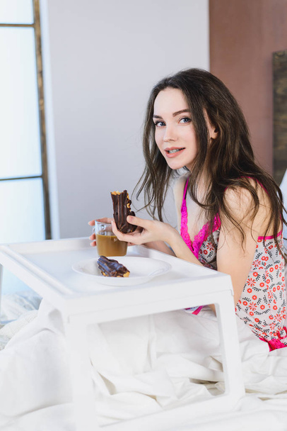 girl with a cake in the bed drinking coffee on the window background - Foto, imagen