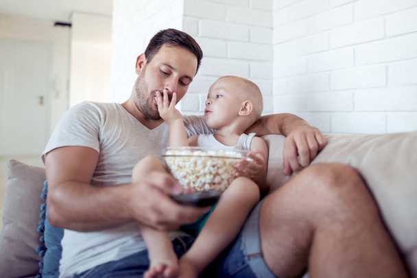 father and little son eating popcorn at home - Photo, Image