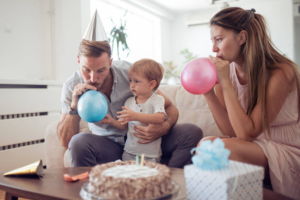 Familia feliz celebrando hijo segundo cumpleaños en casa con pastel
 - Foto, Imagen