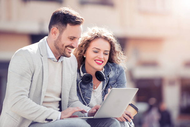 Feliz joven pareja divirtiéndose al aire libre y sonriendo, mirando en la tableta
. - Foto, Imagen
