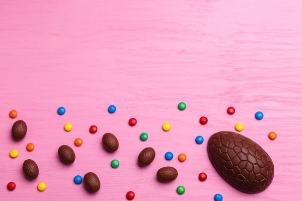 Chocolate Easter eggs and colorful candies on a bright pink background. Easter sweet concept. - Fotografie, Obrázek
