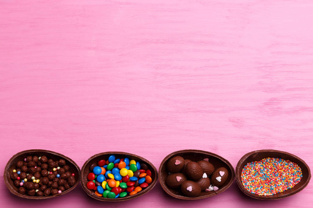 Chocolate Easter eggs and colorful candies on a bright pink background. Easter sweet concept. - Photo, Image