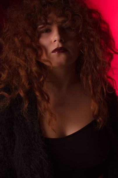Beautiful red-haired girl with curly hair in the studio on a fabric background - Fotografie, Obrázek