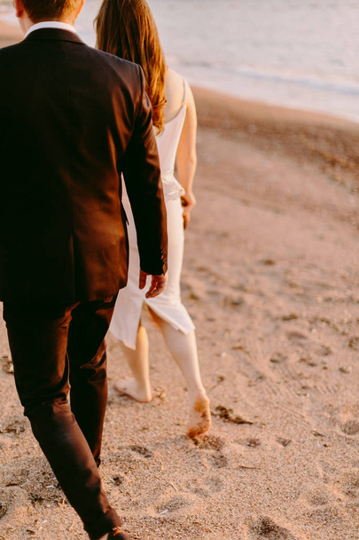 пара гуляє на піщаному пляжі босоніж під час заходу сонця. Медовий місяць
 - Фото, зображення