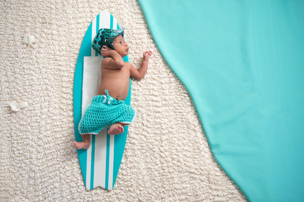 Niño recién nacido en tabla de surf
 - Foto, imagen