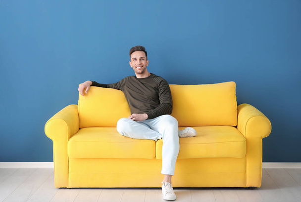 Handsome young man sitting on sofa, indoors - Фото, зображення