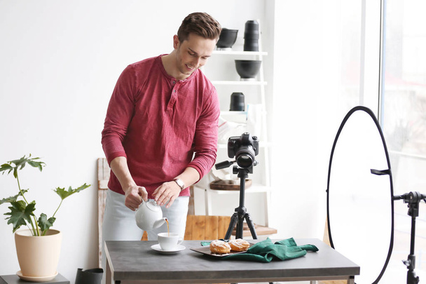 Young man with professional camera preparing food composition in photo studio - Fotoğraf, Görsel