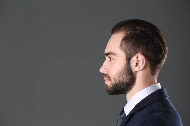 Portrait of young businessman with beautiful hair on grey background - 写真・画像