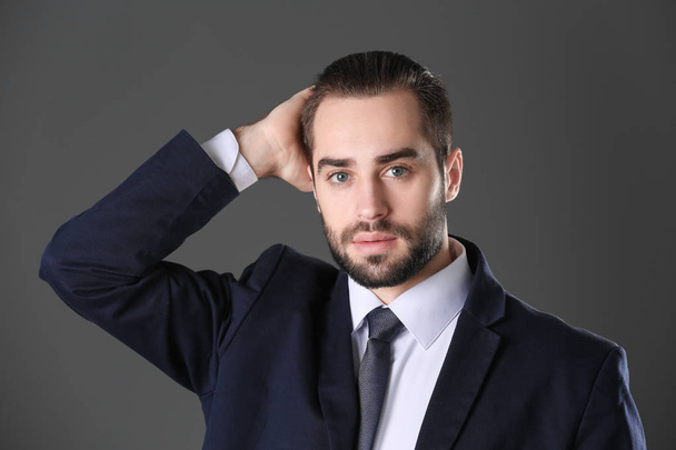 Portrait of young businessman with beautiful hair on grey background - Foto, afbeelding