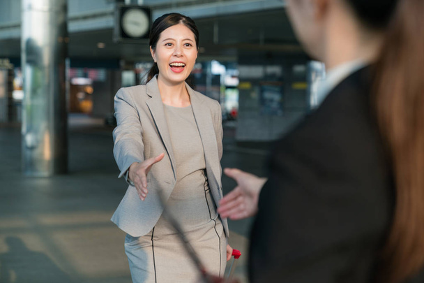 Female business people greeting in a station. - 写真・画像