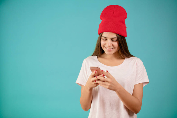 businesswoman in red cap and casual clothing holding and using mobile phone - Foto, Imagem