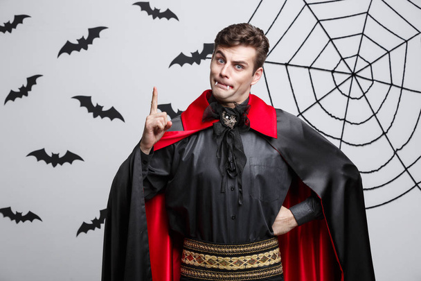 Vampire Halloween Concept - Portrait of handsome caucasian in Vampire halloween costume poining on side.  - Zdjęcie, obraz