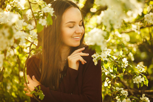 young woman with clean skin near a blooming apple tree. portrait of girl in spring park. - Photo, image
