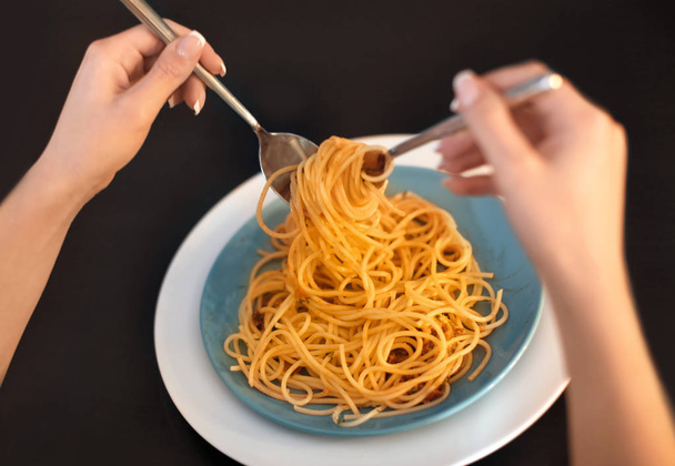 Young woman eating tasty pasta at table, closeup - 写真・画像