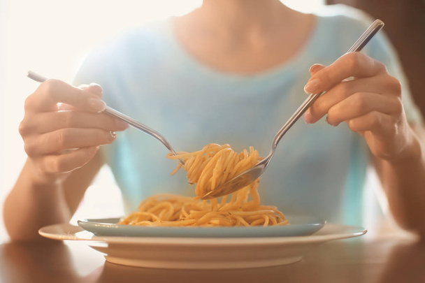 Jonge vrouw smakelijke pasta eten aan tafel, close-up - Foto, afbeelding