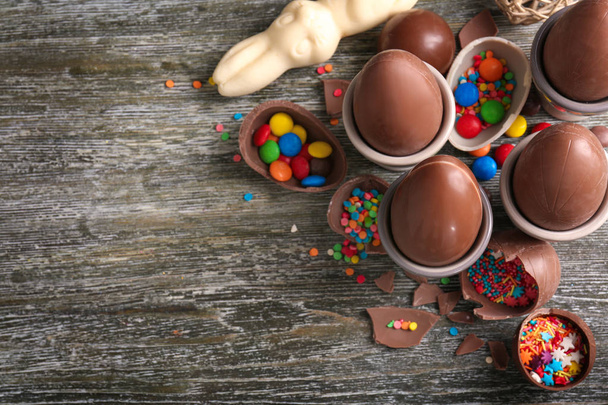 Прекрасна Великодня композиція з шоколадним кроликом, яйцями та цукерками на дерев'яному фоні
 - Фото, зображення