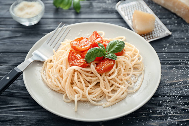 Тарелка вкусной пасты с помидорами и сыром на столе
 - Фото, изображение