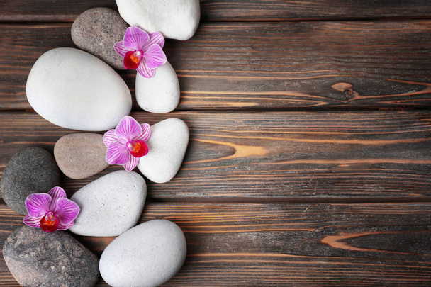 Spa stones and beautiful flowers on wooden background, top view - Foto, Imagen