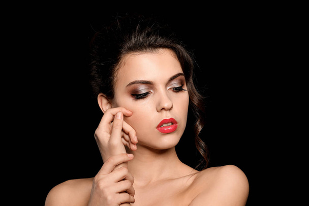 Портрет молодой женщины с красивым профессиональным макияжем на темном фоне - Фото, изображение
