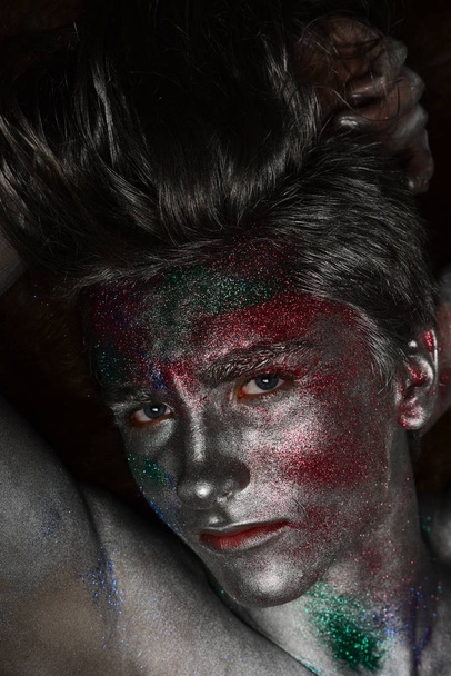 Fashion and art concept. Man covered with shimmering silver paint - Photo, Image