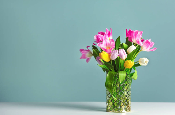 Wazon z piękne tulipany na stole przed kolor tła - Zdjęcie, obraz