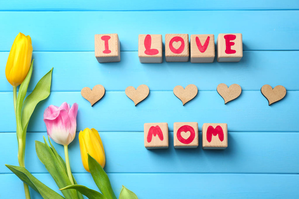 Bloques de madera con letras que forman frase I LOVE MOM y hermosas flores sobre fondo de color
 - Foto, imagen