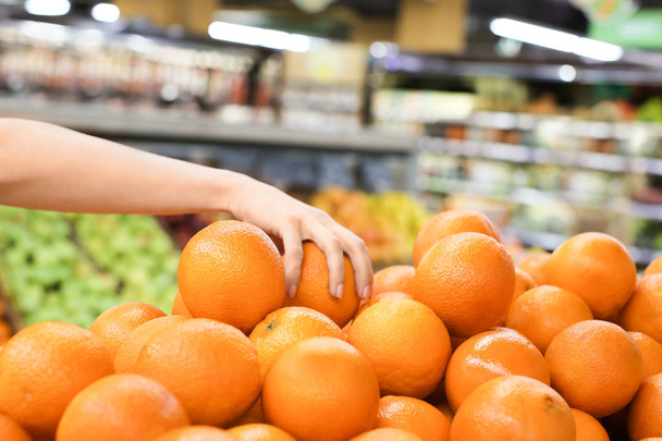 市場で新鮮な熟した柑橘系の果物を選択する若い女性 - 写真・画像