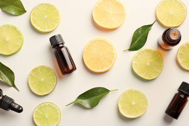 Bottles of essential oils and citrus slices on light background, top view - Foto, Imagem