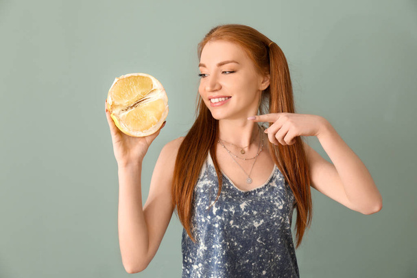 Beautiful young woman with citrus fruit on color background - Photo, Image
