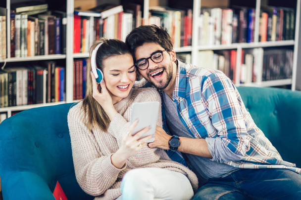 junges Paar nutzt digitales Tablet, hört Musik und vergnügt sich im Café  - Foto, Bild
