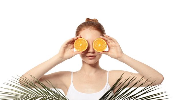 Funny young woman with citrus fruit and palm leaves on white background - Φωτογραφία, εικόνα