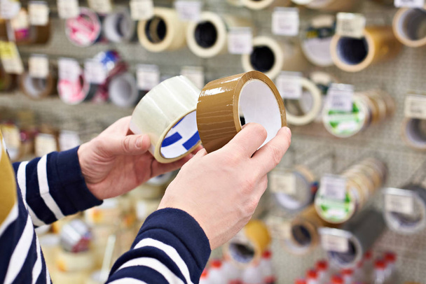 Man buyer chooses adhesive duct tape in store - Zdjęcie, obraz