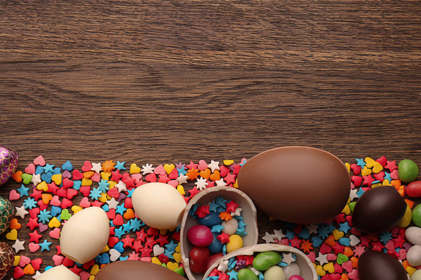 Composizione con cioccolato Uova di Pasqua, zuccherini colorati e caramelle su sfondo di legno
 - Foto, immagini