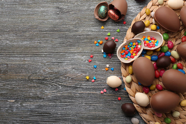 Čokoládová velikonoční vejce, barevné sypání a cukroví na dřevěné pozadí - Fotografie, Obrázek