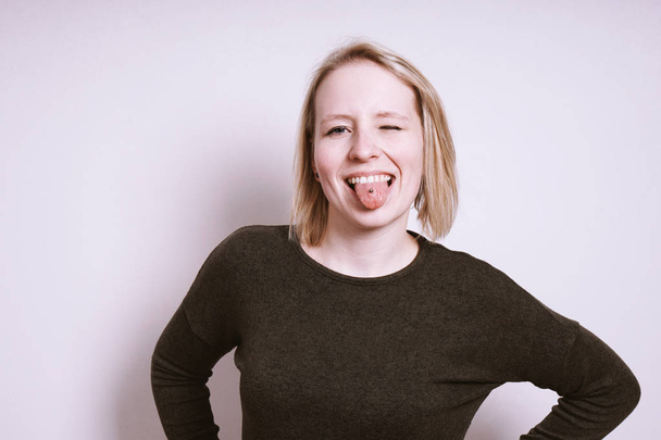 Dumme junge Frau streckt die Zunge heraus und zwinkert - Foto, Bild