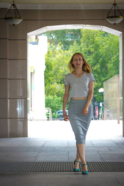 A girl in a gray dress is walking through the summer city - Foto, afbeelding