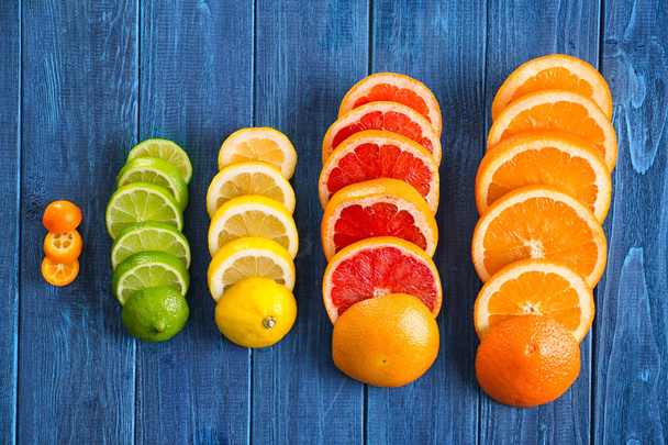 Slices of fresh citrus fruits on wooden table, flat lay - Photo, Image