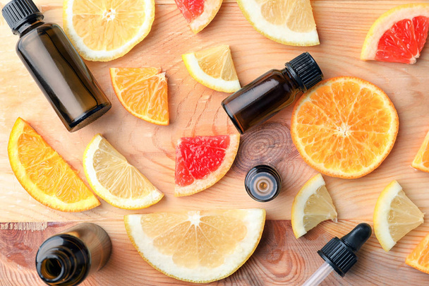 Bottles of essential oil and citrus slices on wooden table - Photo, Image
