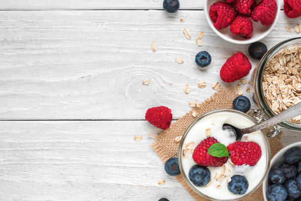 sağlıklı berry Yoğurtlu yulaf ve nane bir bardak beyaz ahşap masa üzerinde bir kaşıkla. sağlıklı kahvaltı - Fotoğraf, Görsel